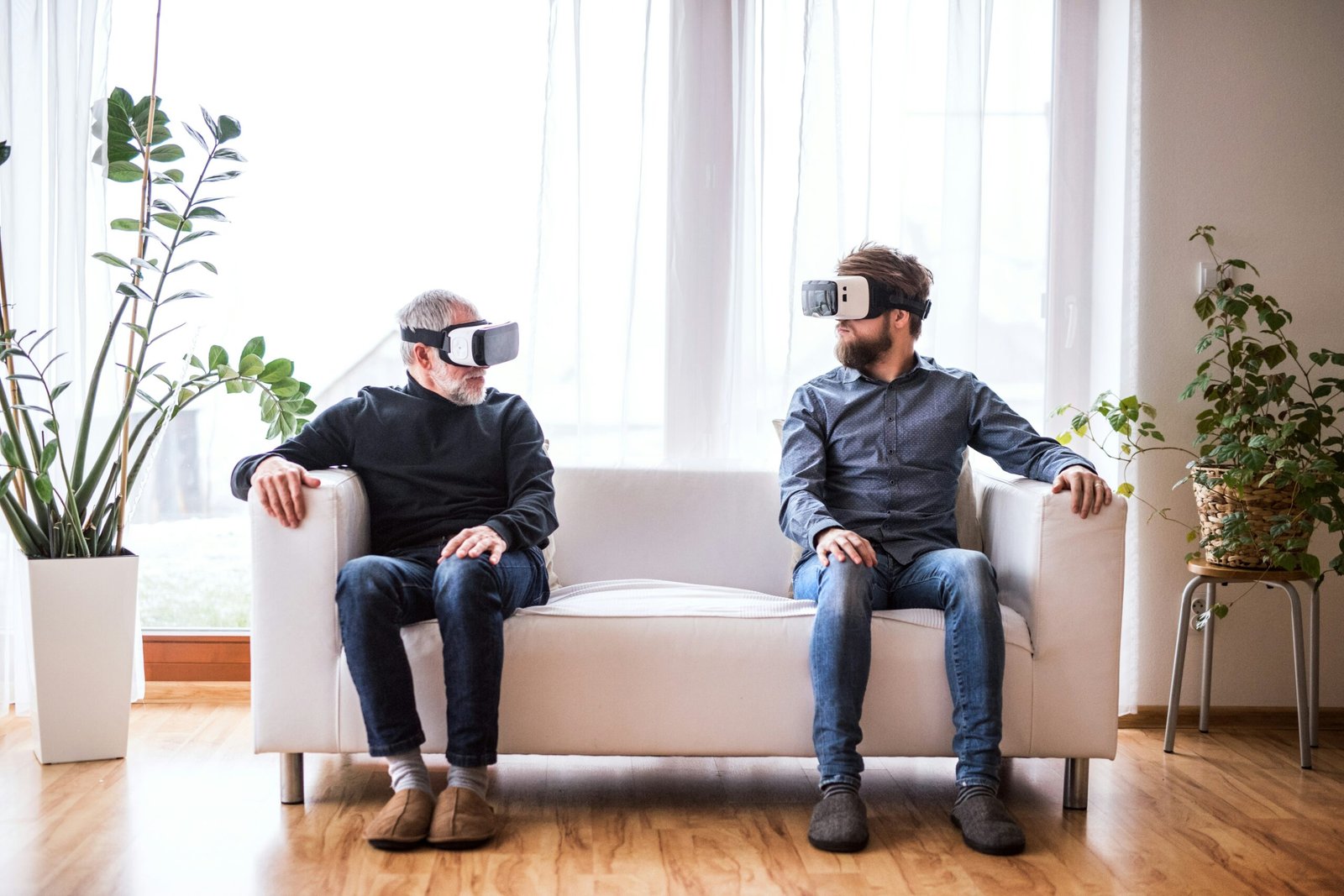 Two men on a sofa looking at each other with VR headsets